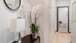 Un couloir avec une orchidée en pot, un miroir et une lampe posée sur une console.