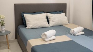 A neatly made bed with a grey headboard, two pillows, and a blue bedspread. - Apartment 'Deluxe' with Sea View, Wi-Fi and Air Conditioning (Ρόδος)