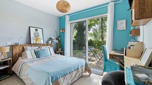Une chambre à coucher comprenant un lit, un bureau, une chaise, un luminaire suspendu et une vue sur l’extérieur.
