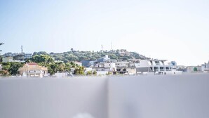 Blick auf eine Stadtlandschaft mit Gebäuden und Grünflächen, bewölkter Himmel und ein Tisch mit Blumen.