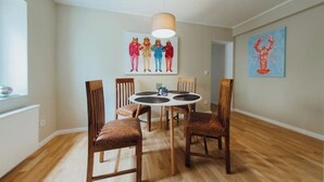 Ein Essbereich mit einem runden Tisch, vier Holzsesseln, einer Deckenleuchte und zwei Bildern an den Wänden.