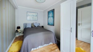 Ein Schlafzimmer mit Bett, Nachttisch, Lampe und Tür.