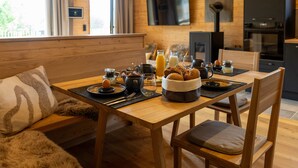 Un tavolo da pranzo in legno con cibarie per la colazione, un divano e una televisione in una stanza in stile baita.
