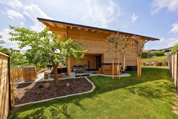 A modern house with a patio, a tree, and a wooden fence.