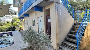 A building with a blue staircase and a small pool area. - Third Base (La Libertad)