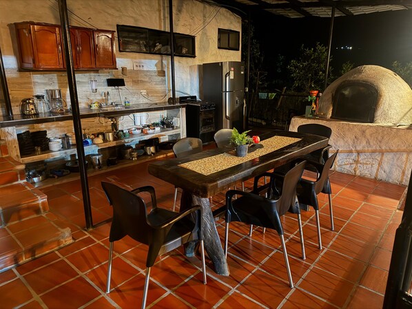 A kitchen with a dining area, including a table with chairs, a built-in oven, and a refrigerator.