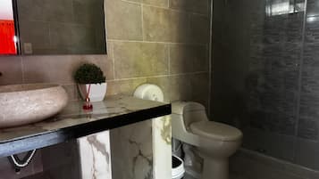 A bathroom with a marble sink, a toilet, and a shower area.