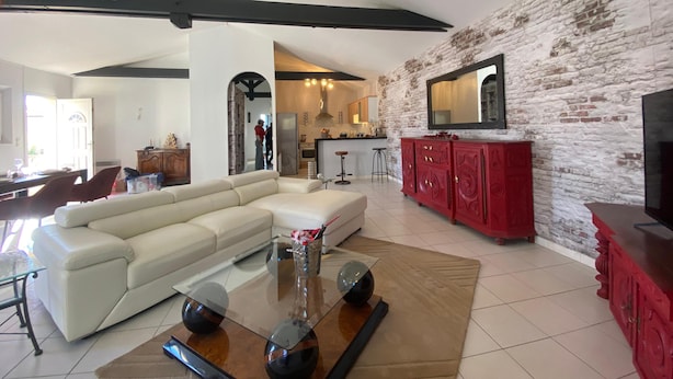Uma sala de estar espaçosa com um sofá branco, uma mesa de centro de vidro e um armário vermelho.