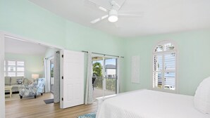 A bedroom with a bed, a ceiling fan, and a view of the outside balcony. - The Sandy Seahorse (Fort Myers Beach)