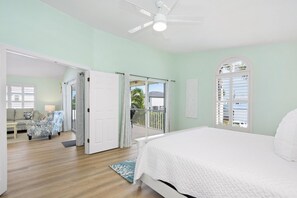 A bedroom with a bed, a ceiling fan, and a view of the outside balcony. - The Sandy Seahorse (Fort Myers Beach)