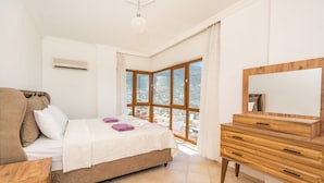 Une chambre à coucher comprenant un lit, une commode en bois, une fenêtre avec vue et un appareil de climatisation.