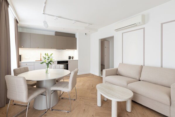 Un salon moderne avec une table à manger ronde, un canapé beige et une petite table basse.