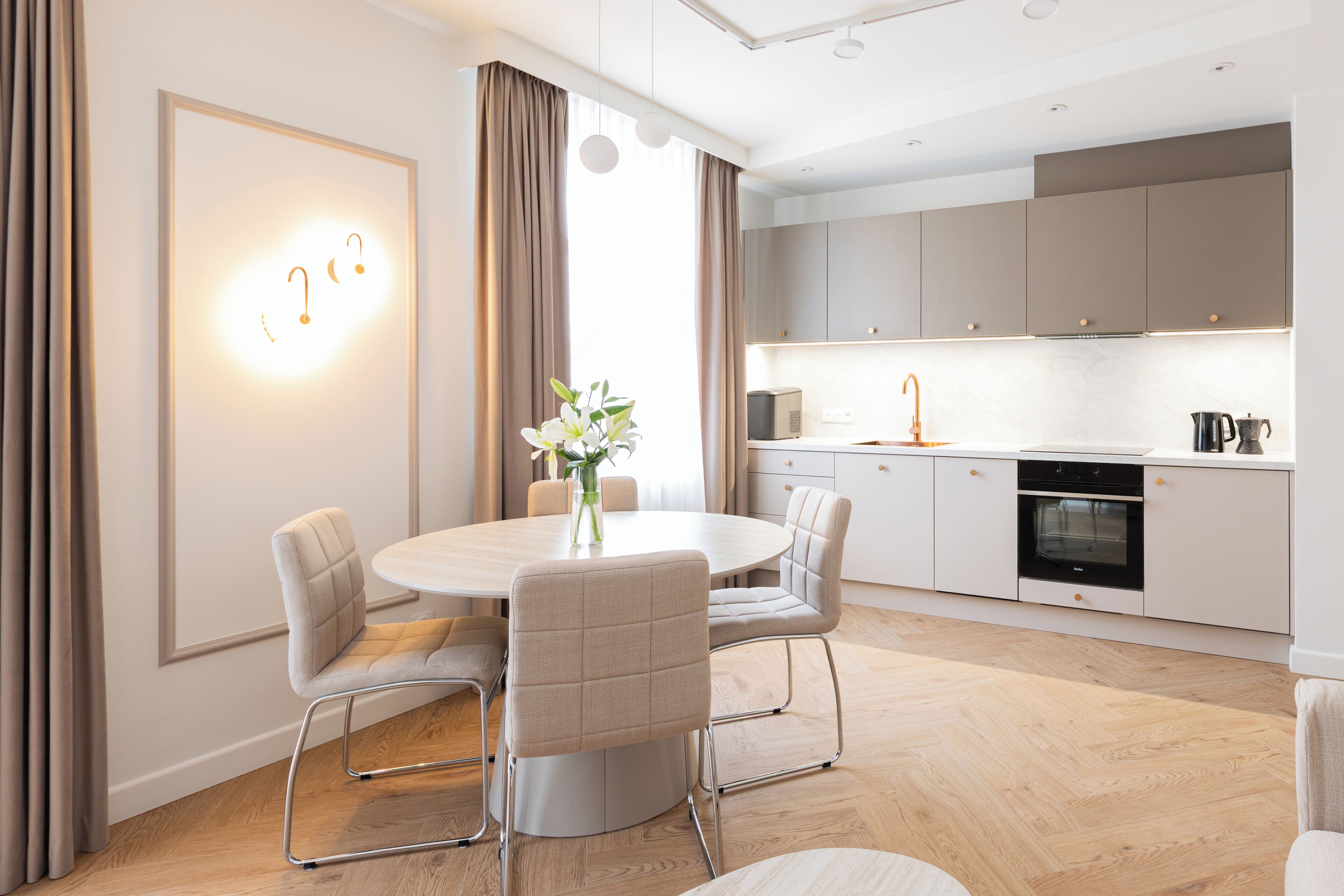 Une cuisine moderne avec une table de salle à manger ronde, des chaises et un vase rempli de fleurs.