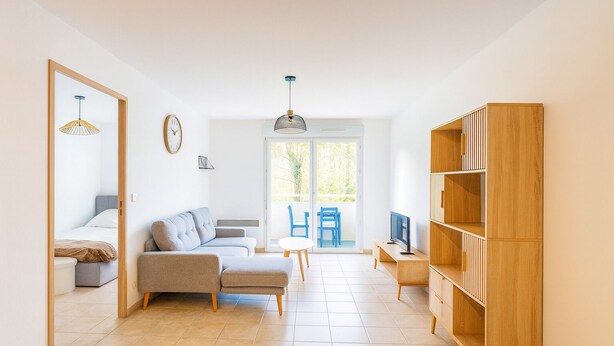 A modern living room with a sofa, a TV, and a wooden bookshelf.