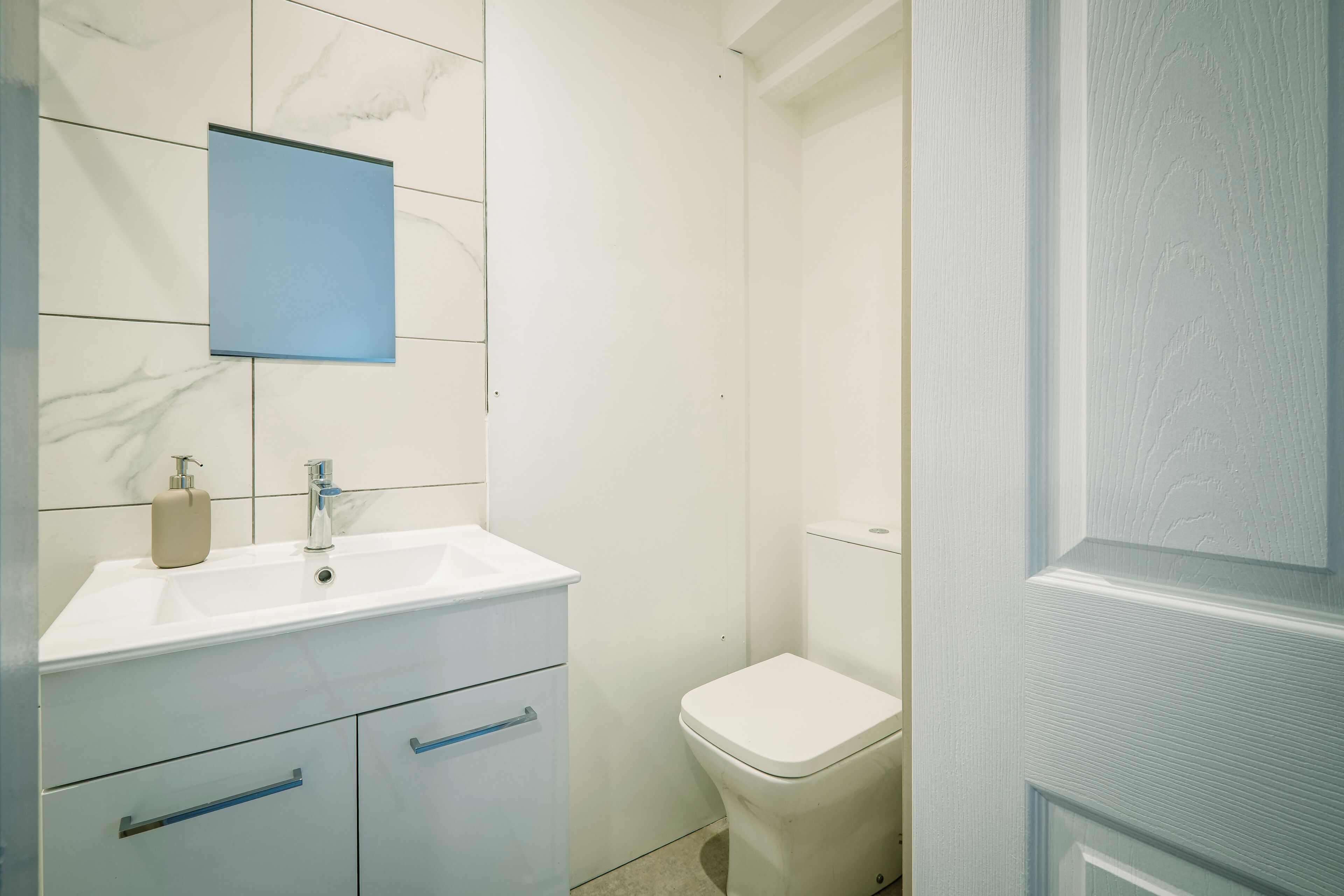 A bathroom with a white sink, a mirror, and a toilet.