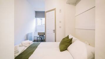 A hotel room with a bed, a desk, and a chair.