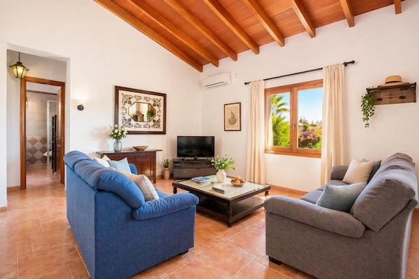 A living room with two sofas, a coffee table, a TV, and a window with curtains. - Villa Gosp Torres Large Private Pool, WiFi (Mallorca)
