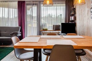 A modern living room with a wooden dining table, grey sofa, and a television on a stand. - Apartment 'Geißenblick 2' with Mountain View, Balcony and Wi-Fi (Braunlage)