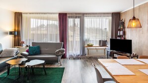 Een moderne woonkamer met een bank, salontafel, televisie en eethoek.