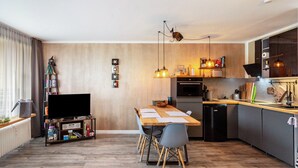 Een moderne keuken met een eettafel, stoelen en een televisie.