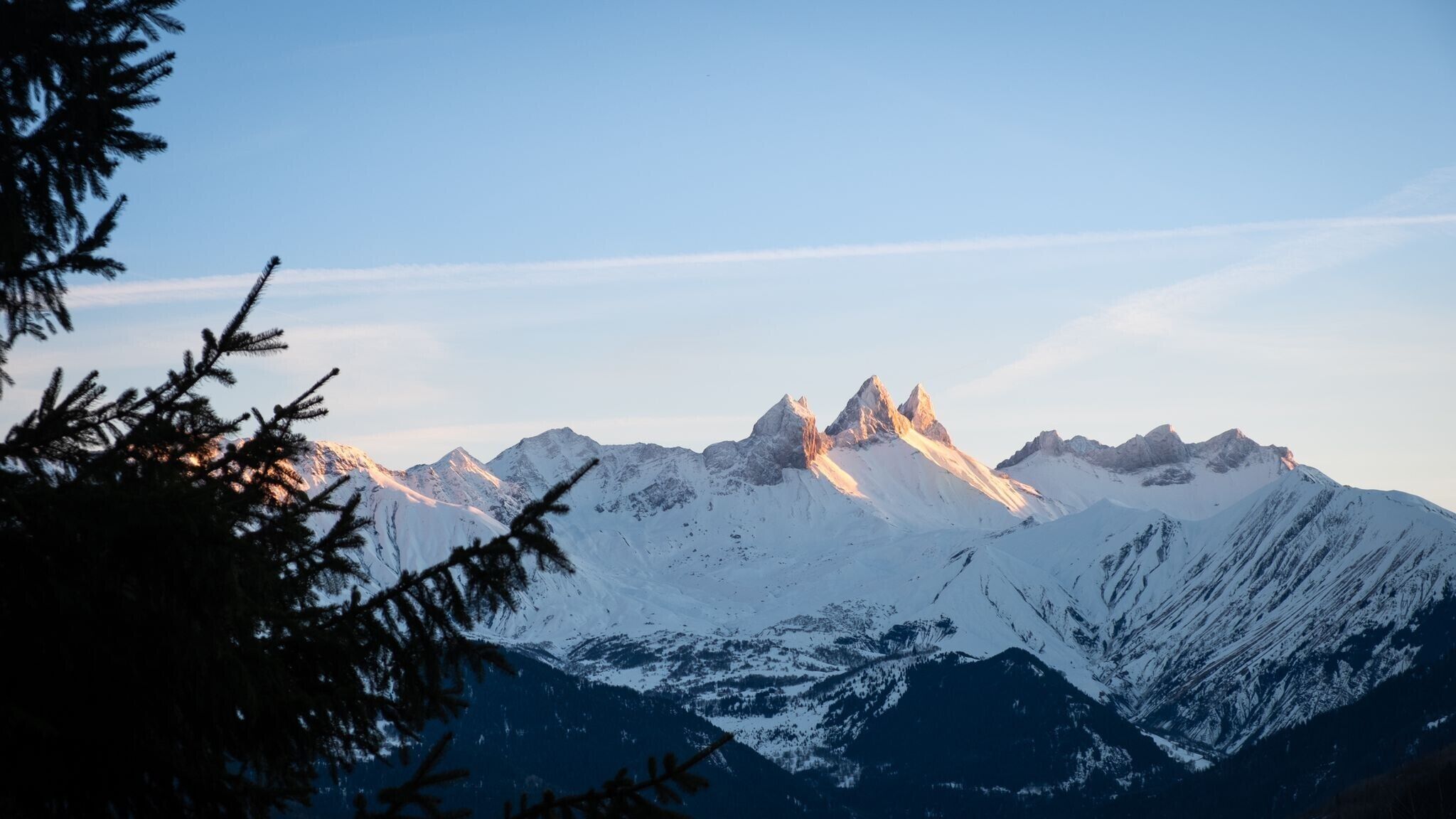 A mountain range with snow-covered peaks and a clear sky.