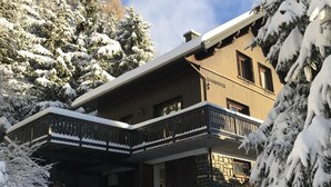 Eine Holzhütte mit Balkon, umgeben von schneebedeckten Bäumen.