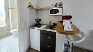 Une cuisine compacte équipée d’un four à micro-ondes, d’un petit réfrigérateur et d’un plan de travail en bois.