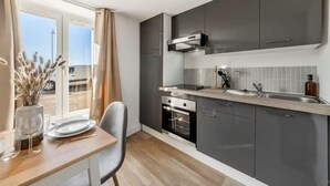 Una cocina moderna con armarios grises, una campana extractora de acero inoxidable y un ventanal con vista a un estacionamiento.