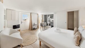 Habitación de hotel moderna con una cama grande, un área de descanso con una silla, un escritorio pequeño y vistas a la ciudad.