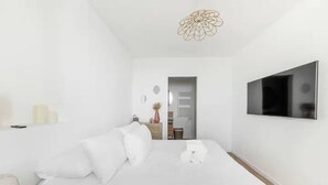 Ein modernes Hotelzimmer mit einem großen Bett, einem Flachbildfernseher und minimalistischer Einrichtung.