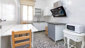 A compact kitchen with white cabinets, a microwave, a sink, and a window with a curtain. - Private room in Mestre with direct bus to Venice (ve)