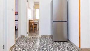 A hallway with a stainless steel refrigerator, a dining area with a table and chairs, and a tiled floor. - Private room in Mestre with direct bus to Venice (ve)