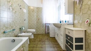 A bathroom with a bathtub, two sinks, a toilet, and a radiator. - Private room in Mestre with direct bus to Venice (ve)