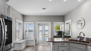 A modern kitchen with a stainless steel refrigerator, white cabinetry, and a granite countertop. - Destin to Relax (Destin)