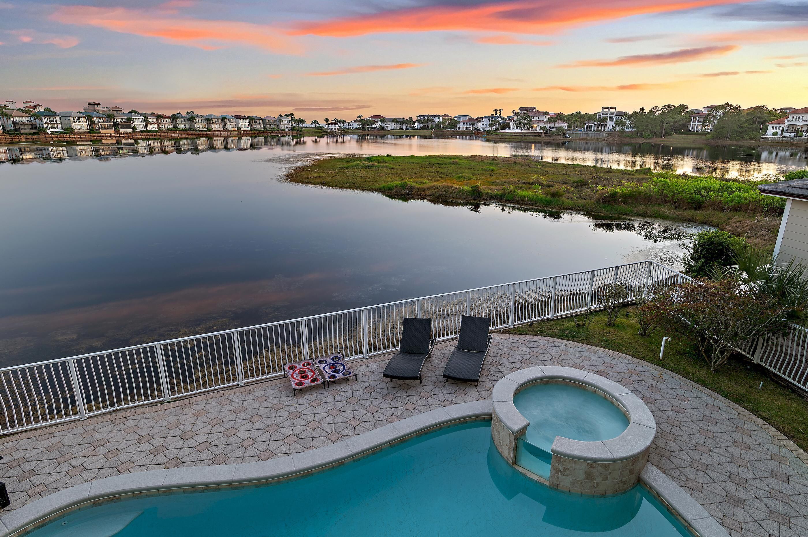 A swimming pool with lounge chairs and a view of a lake and houses.