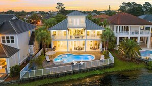 A large two-story house with a swimming pool, surrounded by a fence and palm trees. - Destin to Relax (Destin)