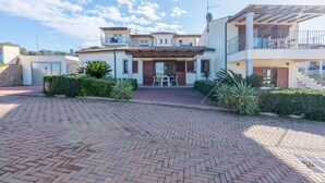 Une maison à plusieurs étages avec une allée pavée, un balcon et un patio aménagé avec du mobilier d’extérieur.