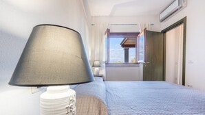 Une chambre à coucher comprenant un lit, une lampe de chevet, une fenêtre et un appareil de climatisation.