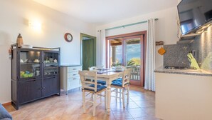 Une cuisine équipée d’une table à manger, de chaises, d’un meuble et d’un téléviseur.