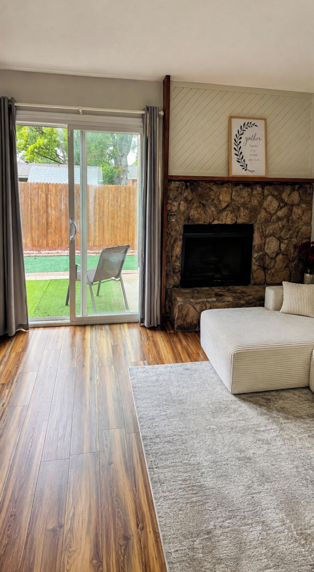 A bedroom with a stone fireplace, a bed, and a sliding glass door leading to a patio.