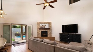 Una sala de estar con sofá modular, chimenea, televisor de pantalla plana y ventilador de techo.