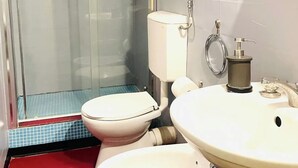 A bathroom with a glass-enclosed shower, a white toilet, and a sink with a mirror. - To complete (Catania)