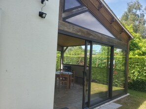 A covered patio area with a table and chairs, a grill, and a view of a garden. - House in Saint Georges d'Oléron—very quiet location near the beaches (Saint-Georges-d'Oléron)