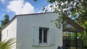 Un edificio blanco con una ventana, una puerta, una parrilla y un patio cubierto de césped.