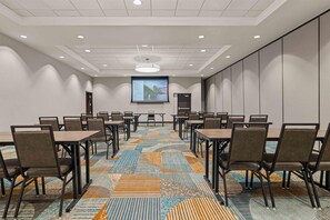 A conference room with a projector screen, multiple tables, and chairs arranged for meetings. - Drury Plaza Hotel Tampa Brandon (Tampa)