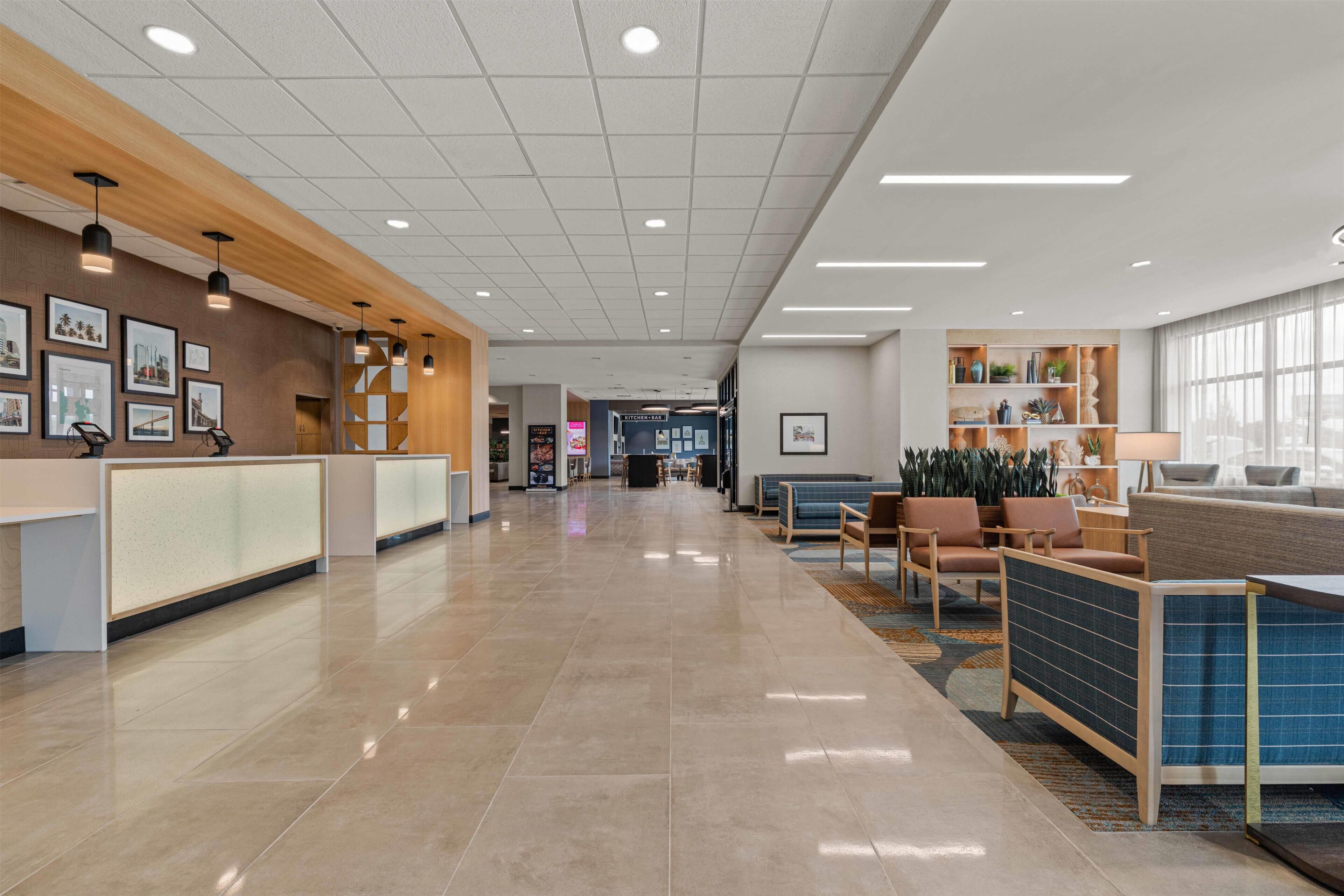 A spacious lobby with a reception desk, seating area, and a large window.