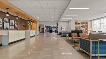 A spacious lobby with a reception desk, seating area, and a large window.