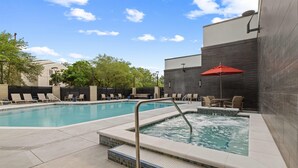 A swimming pool with lounge chairs and a hot tub area, surrounded by a modern building with tiled walls. - Drury Plaza Hotel Tampa Brandon (Tampa)