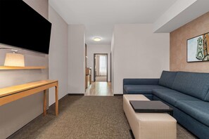 A modern living room with a sofa, a coffee table, a TV, and a lamp. - Drury Plaza Hotel Tampa Brandon (Tampa)