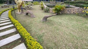 A landscaped garden with a statue of a horse, a giraffe statue, and a building with a blue roof. - SKYGREEN ECOHOTEL (Dosquebradas)
